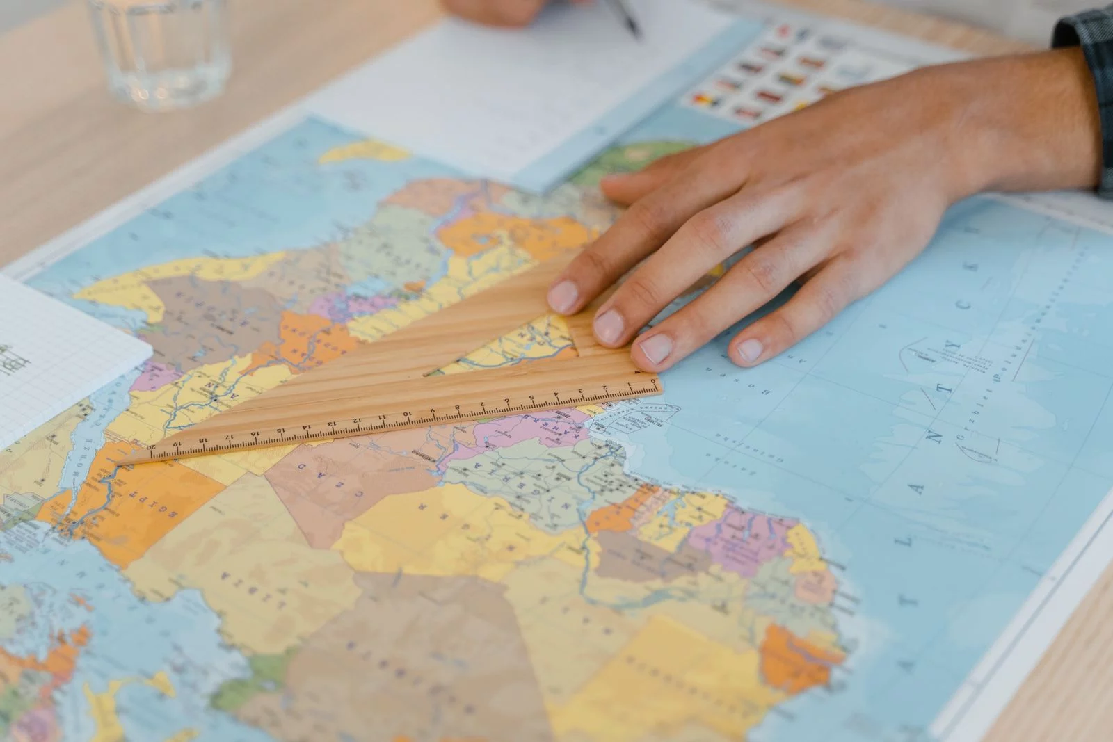 Une main mesure une distance sur une carte du monde à l’aide d’une équerre